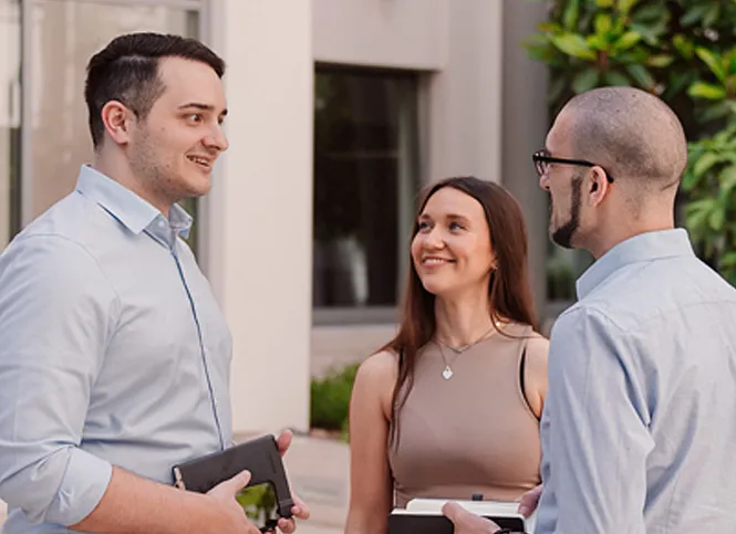Three colleagues are standing in the entrance area talking.