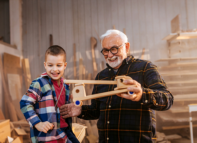 Opa und Enkel spielen mit Holzspielzeug.