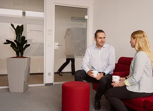 Ein Arbeitskollege tauscht sich mit einer Kollegin über ein Thema aus.