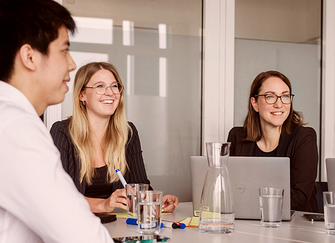 Vier Kolleginnen und Kollegen besprechen ein Thema im Meetingraum.