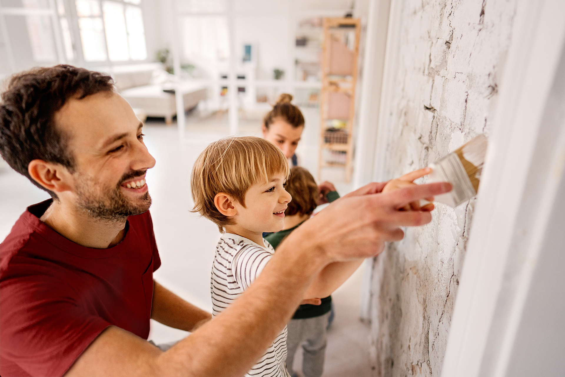 Familie mit zwei Kindern streicht eine Wand.