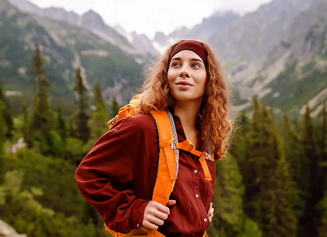 Bergsteigerin blickt fokussiert Richtung Gipfel.