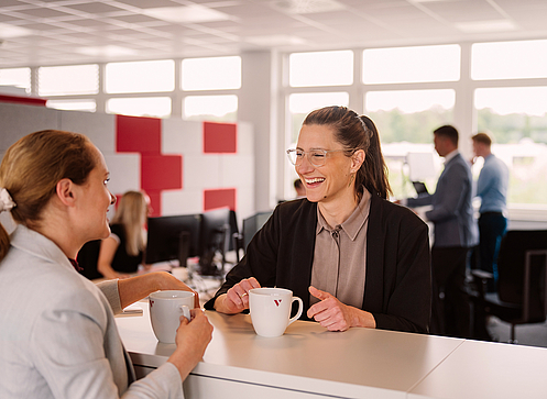 Zwei Kolleginnen trinken Kaffee und unterhalten sich.